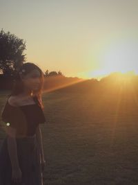 Woman standing on field against clear sky during sunset