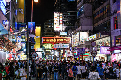 Crowd on city street by buildings at night