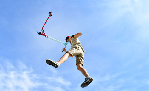 Low angle view of man jumping against sky