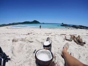 Midsection of woman on beach against clear sky