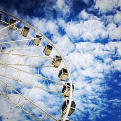Low angle view of ferris wheel against cloudy sky