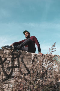Portrait of young man on rock against sky