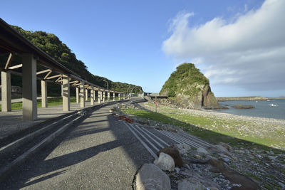 Empty road by sea against sky