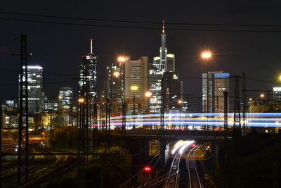 Illuminated railroad tracks against sky at night