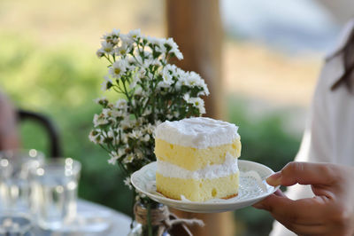 Midsection of person holding ice cream on table