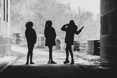 Rear view of silhouette people on footpath in city