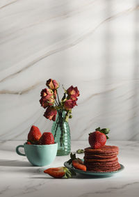 Still life with pink strawberry pancakes on a turquoise plate with sour cream