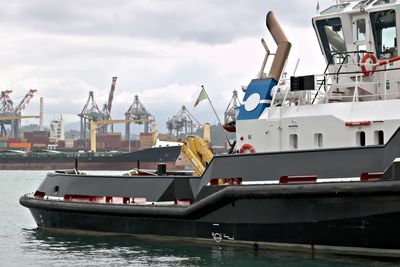 Boats moored at harbor against sky