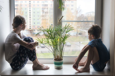 Side view of woman standing against window