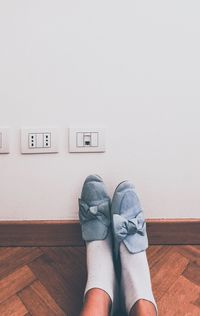 Low section of man standing on hardwood floor against wall