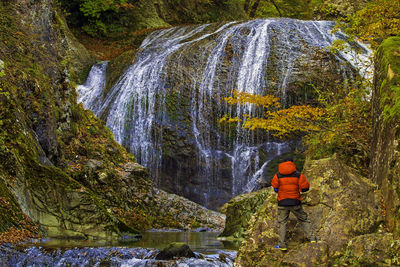 Rear view of man looking at waterfall