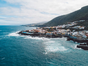 Scenic view of sea by buildings against sky