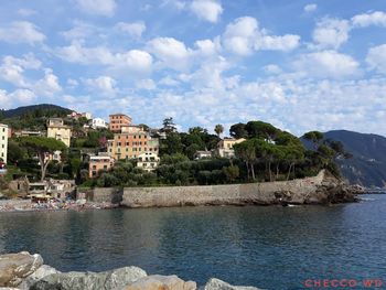 Buildings by sea against sky in city