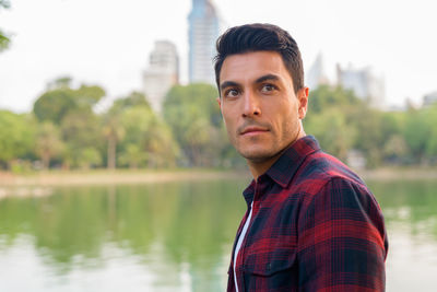 Man looking away while standing against lake