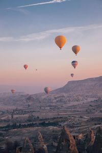 Hot air balloons flying over landscape against sky during sunset