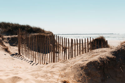 Wooden posts on beach against clear sky