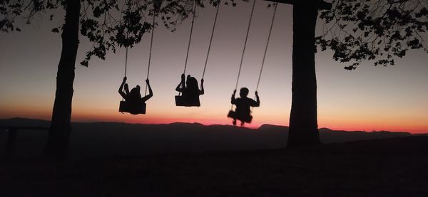 Low angle view of silhouette man swinging against sky during sunset