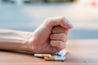 Close-up of hand holding cigarette on table