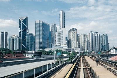 Railroad tracks amidst buildings in city against sky