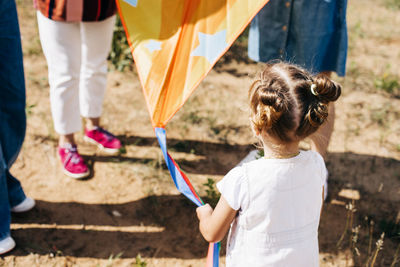 A little girl with her family is flying a kite. rear view. family weekend, family time