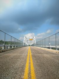 Empty bridge against cloudy sky