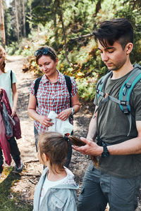 Family with backpacks hiking in a mountains actively spending summer vacation together