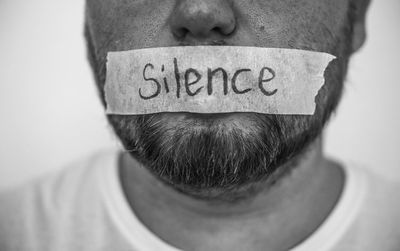 Close-up of man with text on adhesive tape stuck on lips