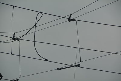 Low angle view of silhouette cables against clear sky