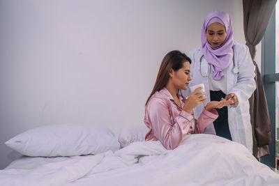 Young woman sitting on bed in bedroom