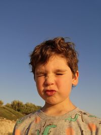 Portrait of boy against clear sky with face expression