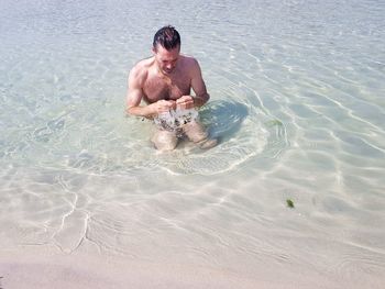 Shirtless man swimming in sea