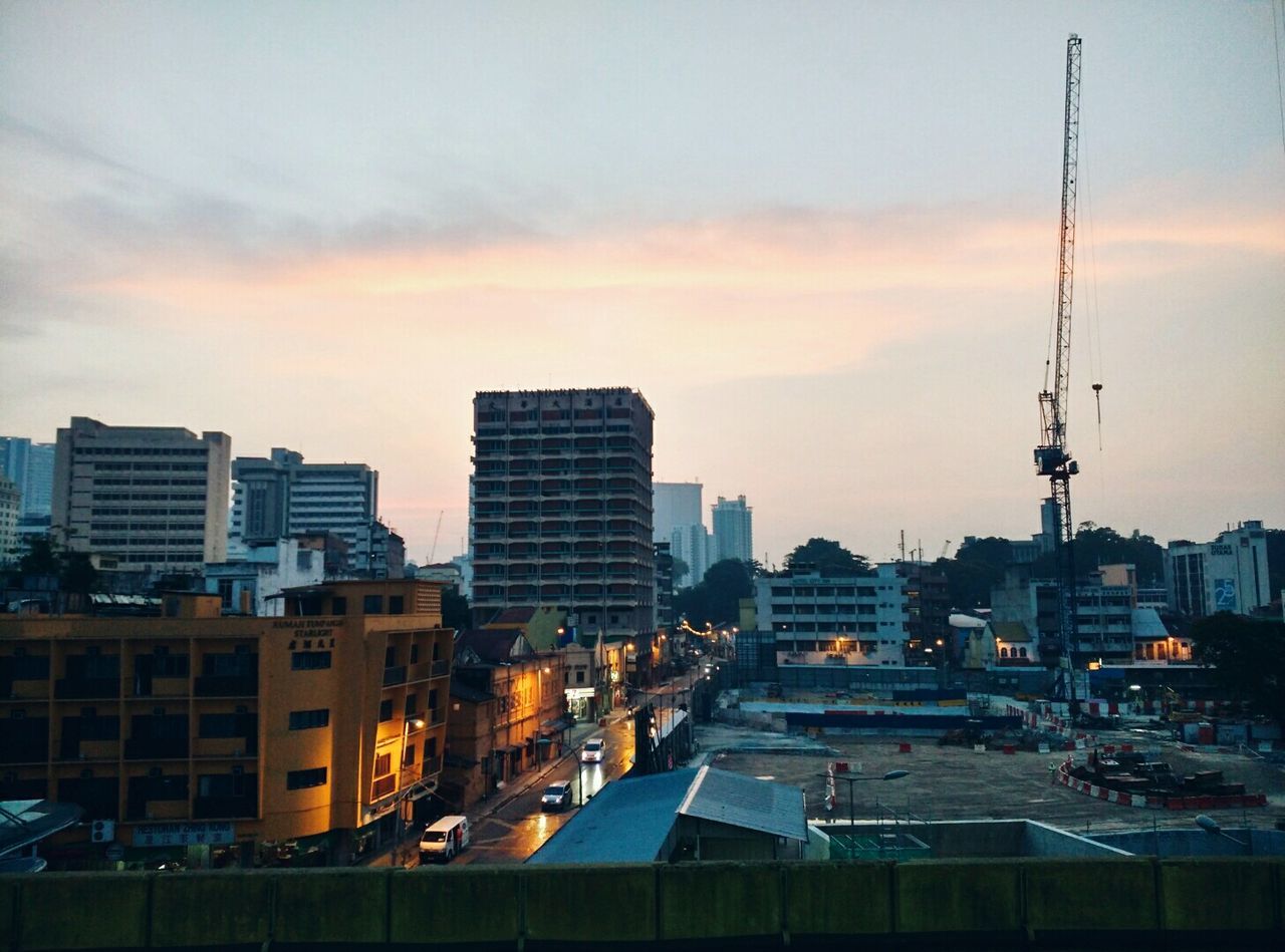 sunset, building exterior, architecture, city, built structure, transportation, sky, mode of transport, cityscape, orange color, cloud - sky, high angle view, skyscraper, development, crane - construction machinery, car, city life, tall - high, dusk, outdoors