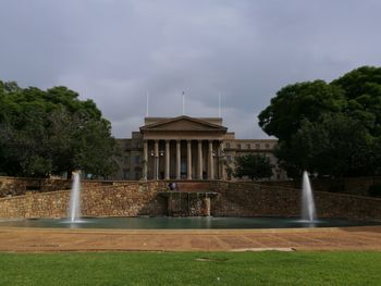 Fountain in front of building against sky