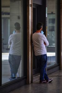 Rear view of man standing at entrance of building