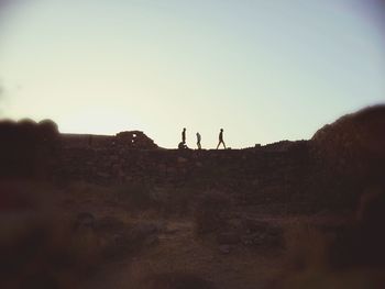 Men on landscape against clear sky