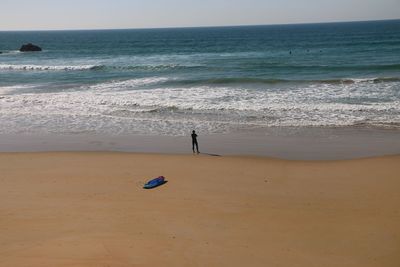 Mid distance of man standing on shore against sea at beach