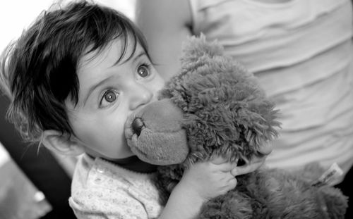 Close-up of cute baby looking up while holding teddy bear