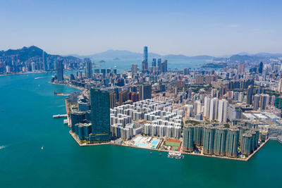 Aerial view of city by sea and buildings against sky