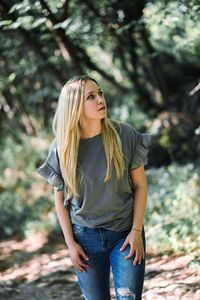 Full length of young woman standing against tree