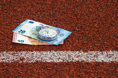 Close-up of stopwatch and paper currencies on field