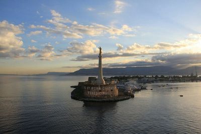 Statue in sea against cloudy sky