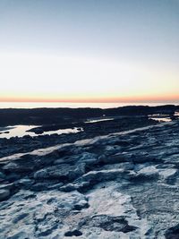 Scenic view of snow covered land against sky during sunset