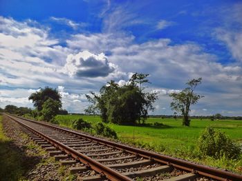 Railroad track amidst field against sky