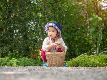 Surface level view of girl with wicker basket on footpath against trees