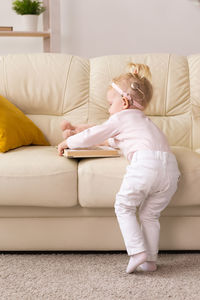 Full length of woman sitting on sofa at home