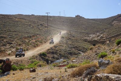 People riding quadbikes on dirt road