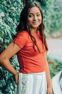 Portrait of a smiling young woman standing by plants outdoors