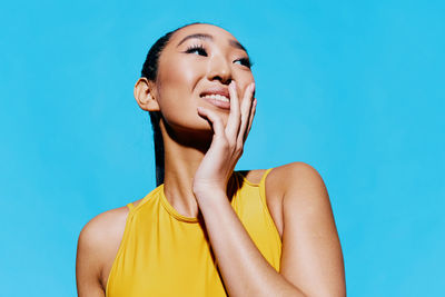 Portrait of young woman against blue background