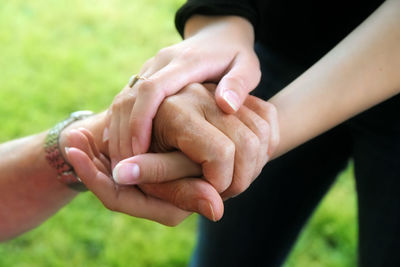 Cropped image of people holding hands over field