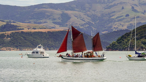 Sailboat sailing on sea against mountains